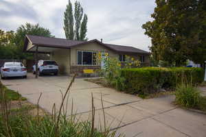 Ranch-style home featuring concrete driveway, an attached carport, a shingled roof, and brick siding