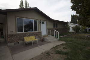 View of front of home with stucco siding, brick siding, a front lawn, and crawl space