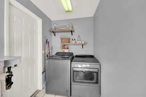 Laundry area featuring washing machine and clothes dryer and light tile patterned floors