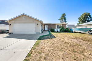 Ranch-style home with concrete driveway, a garage, and a front lawn