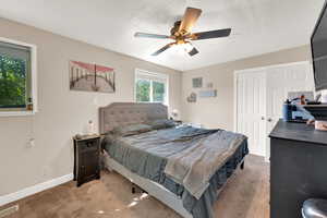 Carpeted bedroom featuring a textured ceiling and ceiling fan