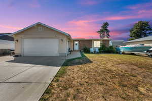 Ranch-style house with driveway, a garage, and a front lawn