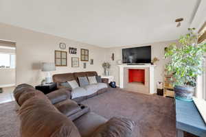 Carpeted living area featuring a tile fireplace and baseboards