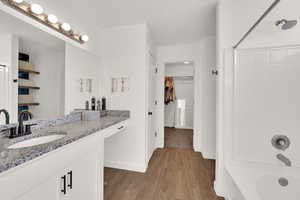 Full bathroom featuring vanity,  shower combination, a spacious closet, and light wood-style flooring