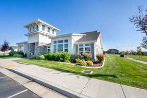 View of front of property with a front yard, stone siding, and uncovered parking