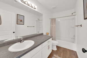 Bathroom featuring shower / bath combo with shower curtain, dark wood-style flooring, and vanity