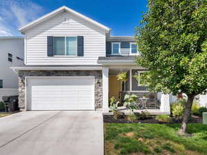 View of front of property featuring stone siding, driveway, and an attached garage
