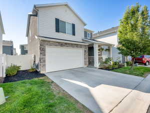 Traditional home with stone siding, a garage, and concrete driveway