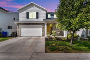 Traditional-style house featuring stone siding, driveway, and a garage