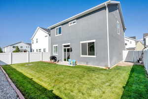 Back of property with a fenced backyard, a gate, stucco siding, and a patio