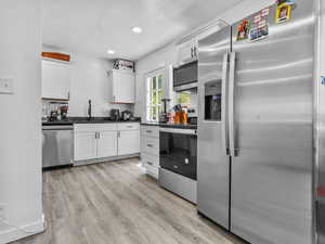 Kitchen with appliances with stainless steel finishes, white cabinetry, light wood-style floors, and recessed lighting