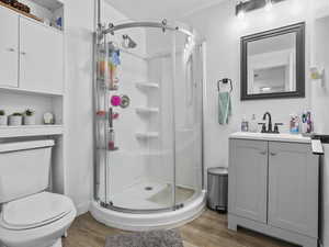 Bathroom featuring vanity, light wood-type flooring, a shower stall, and a textured ceiling