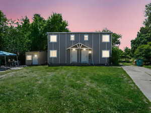 View of front of house with a lawn, a storage unit, and board and batten siding