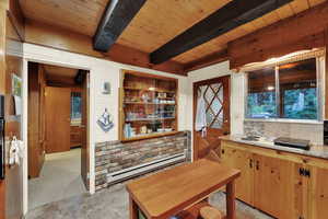 Kitchen featuring light countertops, a baseboard radiator, a wooden ceiling with exposed beams, and wood walls