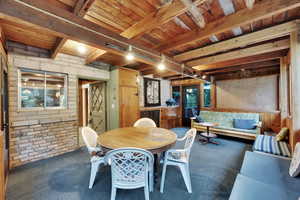 Carpeted enclosed deck with brick wall and a wood ceiling with exposed beams
