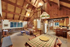 Dining area with a wooden ceiling with exposed beams, baseboard heating, a ceiling fan, high vaulted ceiling, and healthy amount of natural light