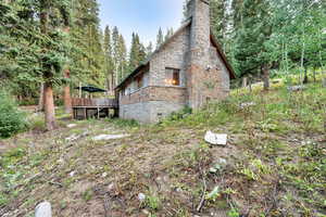 View of side of home featuring brick siding, crawl space, a deck, and a chimney