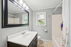Bathroom with shower / bath combo, light tile patterned floors, vanity, and ornamental molding