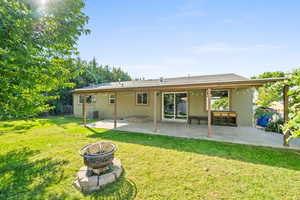 Rear view of house featuring a patio, stucco siding, a fire pit, and a lawn