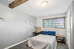 Carpeted bedroom with a closet and beam ceiling