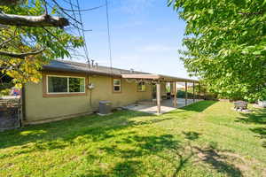 Back of property with stucco siding, a patio, a yard, and a fire pit