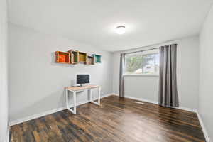 Unfurnished office with dark wood-style flooring and baseboards