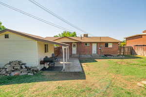 Rear view of house featuring brick siding, a patio, entry steps, a fenced backyard, and roof with shingles