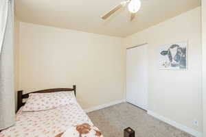 Carpeted bedroom with ceiling fan and a closet