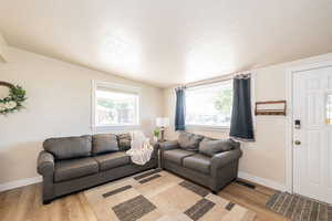 Living room with a textured ceiling, light wood-style floors, healthy amount of natural light, and lofted ceiling