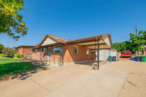 Ranch-style home featuring concrete driveway, a patio area, a carport, brick siding, and a storage shed