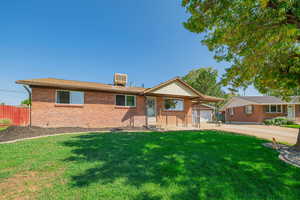 Single story home featuring a front yard, brick siding, and driveway
