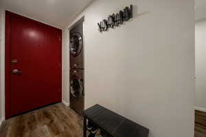 Laundry room with dark wood finished floors and stacked washer / drying machine