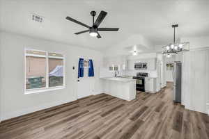 Kitchen with light countertops, stainless steel appliances, lofted ceiling, open floor plan, and white cabinets