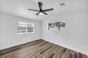 Spare room with wood finished floors, vaulted ceiling, and ceiling fan