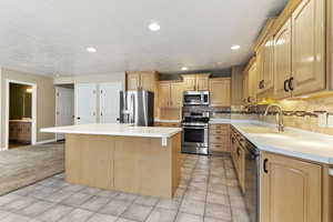 Kitchen featuring a kitchen island, light tile patterned floors, light countertops, and recessed lighting