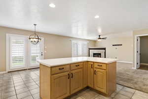 Kitchen with a fireplace, a center island, light countertops, light tile patterned floors, and open floor plan