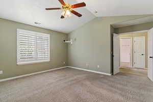 Unfurnished bedroom with light colored carpet, lofted ceiling, ceiling fan, and a textured ceiling