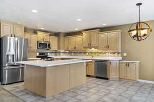 Kitchen with stainless steel appliances, light brown cabinets, light countertops, tasteful backsplash, and recessed lighting