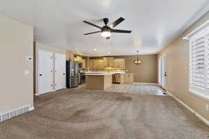 Kitchen featuring light countertops, light carpet, a center island, stainless steel appliances, and open floor plan