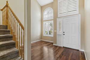 Entryway featuring stairway, dark wood-type flooring, and a towering ceiling