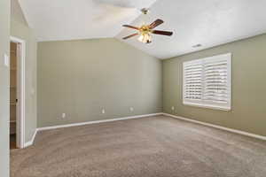 Primary  bedroom featuring carpet floors, lofted ceiling, a textured ceiling, and ceiling fan