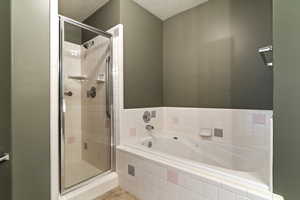 Full bathroom with a stall shower, a bath, a textured ceiling, and tile patterned floors