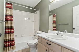 Bathroom with shower / bath combo with shower curtain, vanity, and light tile patterned flooring