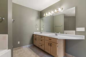 Primary bathroom with double vanity, light tile patterned floors, and tiled seperate bath and shower