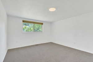 Carpeted spare room featuring baseboards