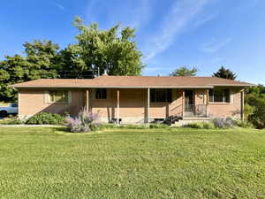 Single story home with brick siding, a front lawn, and a porch