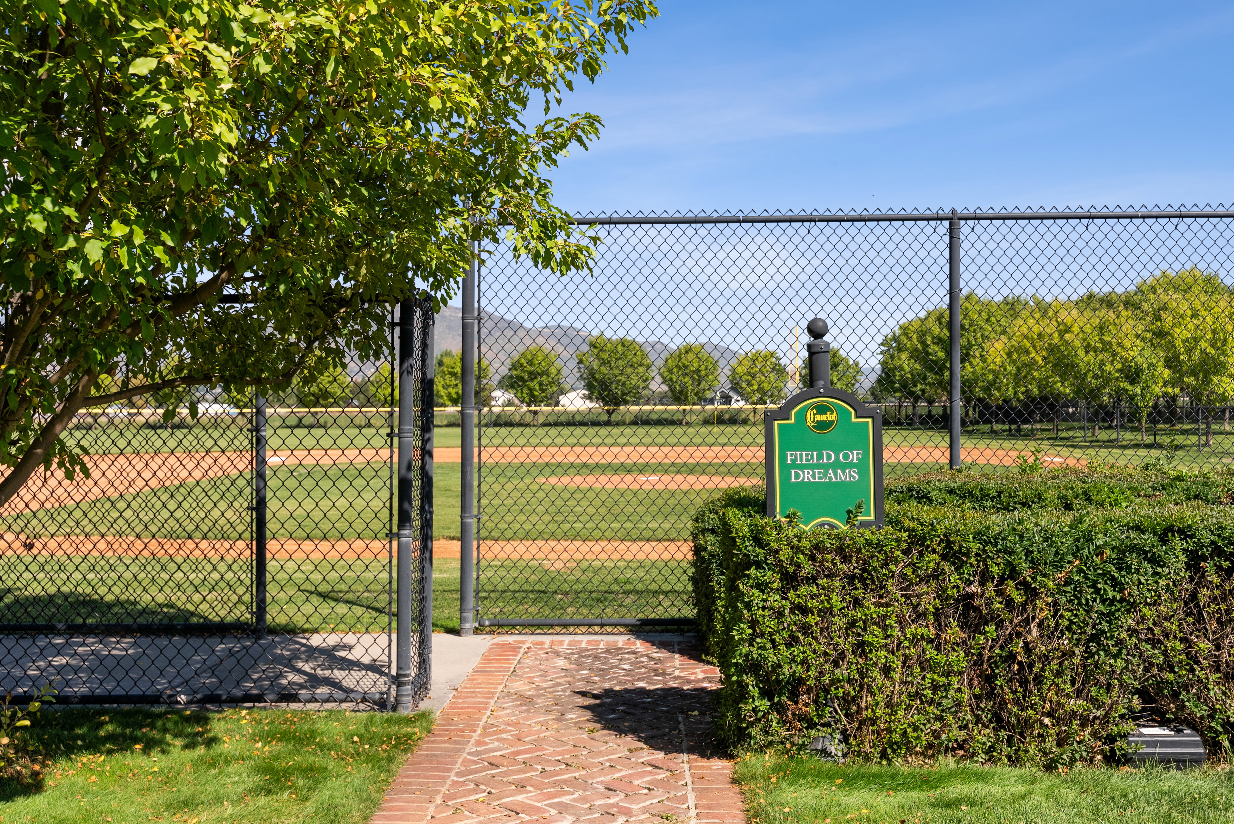 Baseball field with a chain-link fence, green outfield, and dirt infield