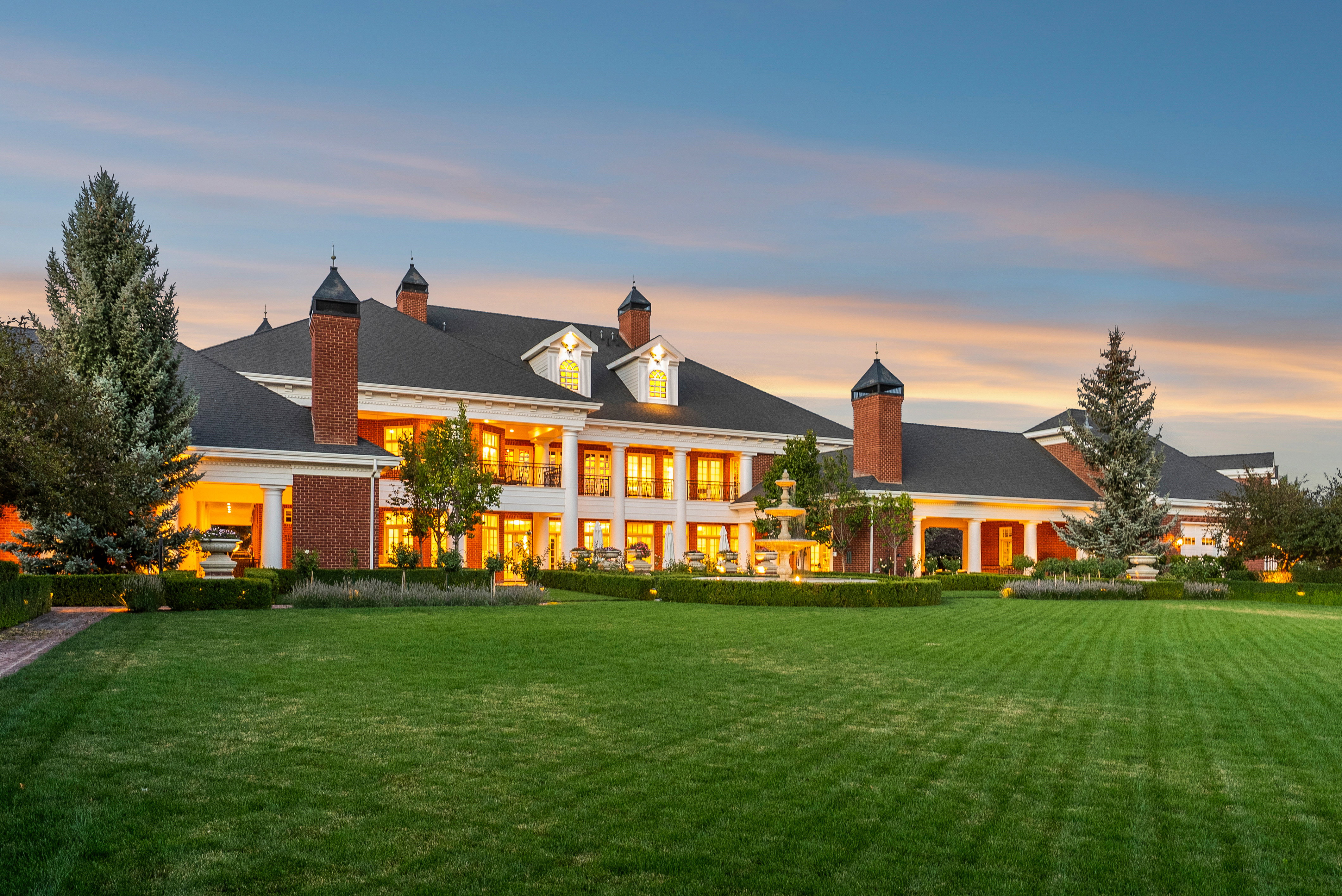 Expansive green lawn fronting a grand brick and white-columned estate
