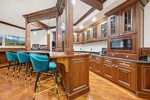 Kitchen featuring brown cabinetry, glass insert cabinets, a kitchen breakfast bar, ornamental molding, and decorative backsplash