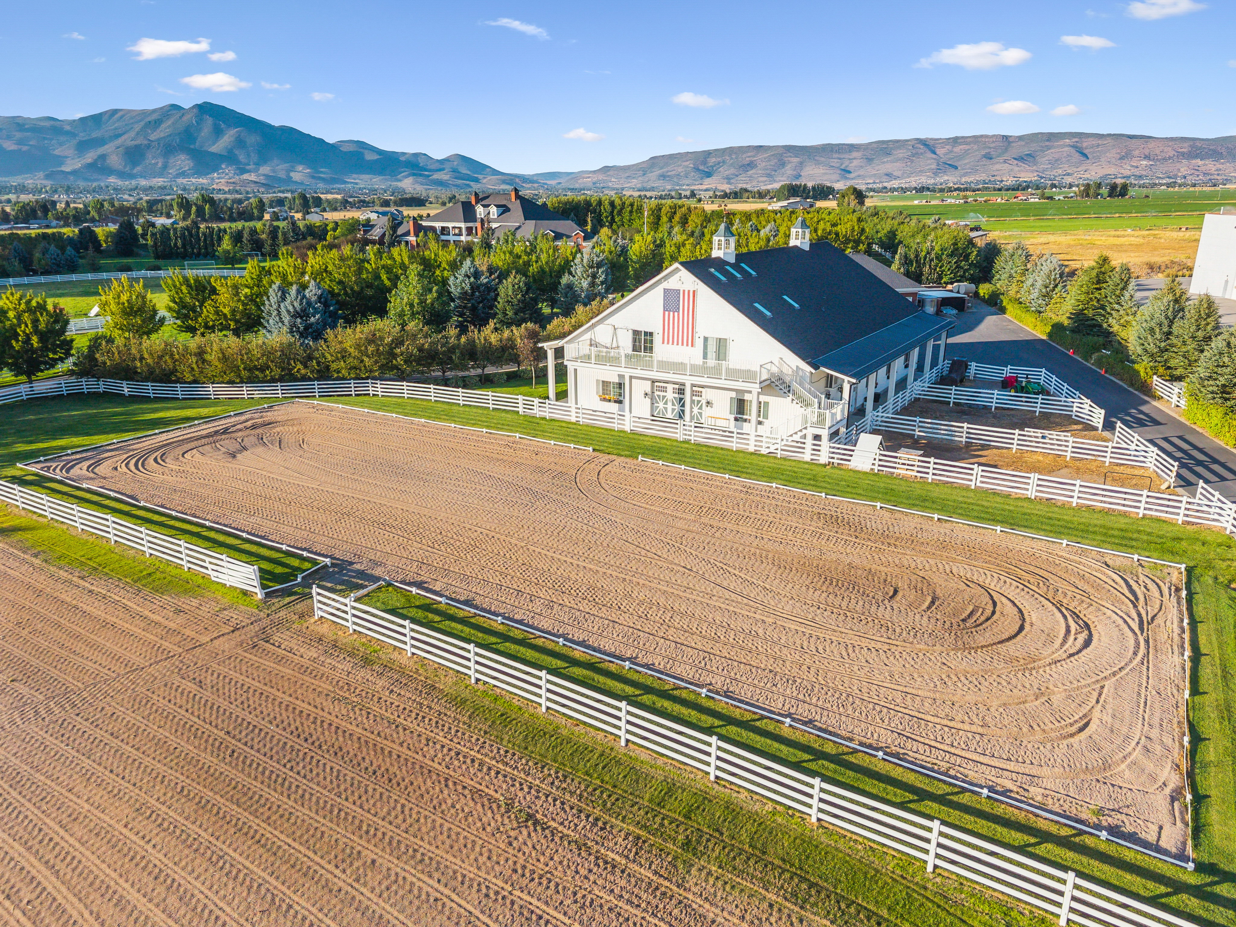 Expansive outdoor arena featuring a sand surface and white perimeter fencing